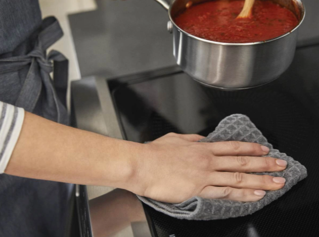 Close view of someone cleaning sauce off of an active Frigidaire Gallery induction range